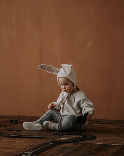 Toddler baby boy in funny bunny hat playing with toy car