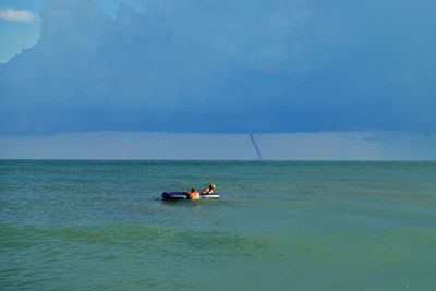 People on boat in sea against sky