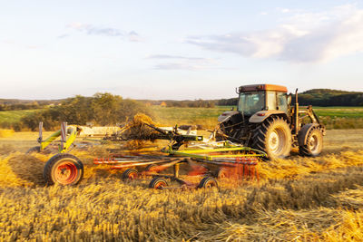 Tractor collecting straws on field