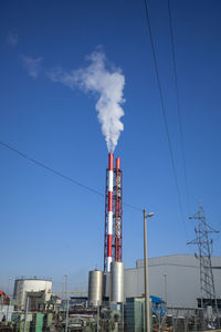 Smoke emitting from factory against blue sky