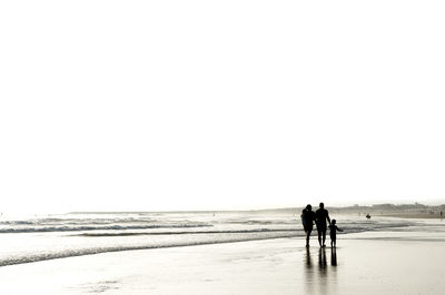 Rear view of family walking at beach