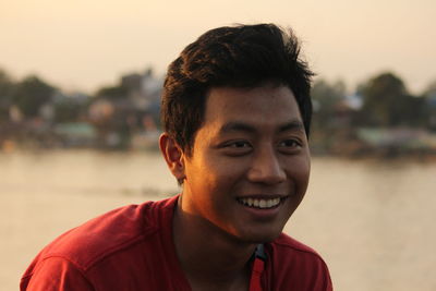 Portrait of smiling young man against sky during sunset