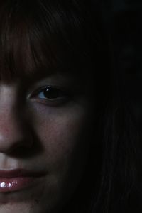 Close-up portrait of woman against black background