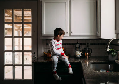 Young boy sitting on counter excited to help making coffee in morning