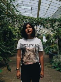 Portrait of beautiful young woman standing against plants