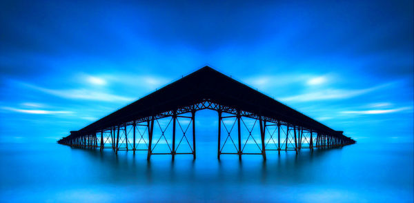 Built structure by sea against blue sky