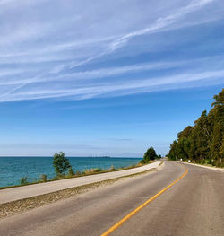 Road by lake against blue sky