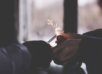 Cropped hands of person holding lit sparklers