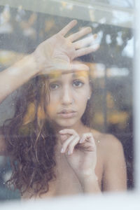 Portrait of young woman looking through window