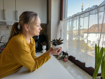 Side view of young man looking through window