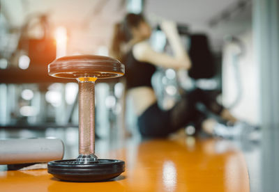 Close-up of dumbbell with woman sitting in background