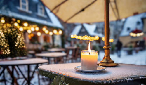 A solitary candle burns brightly on a frost-covered table
