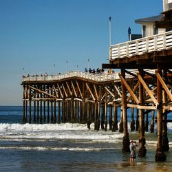 Pier on sea against clear blue sky