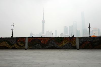 Graffiti on wall by street against cityscape in foggy weather