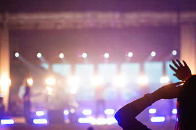 Cropped hand of woman holding illuminated string lights at night