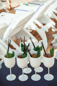 White glasses with tropical cocktails decorated with black straws and banana leaves