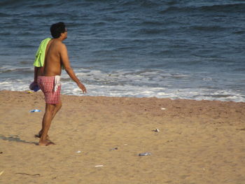 Full length of shirtless man standing on beach