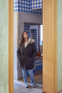 Full length of young woman standing against door