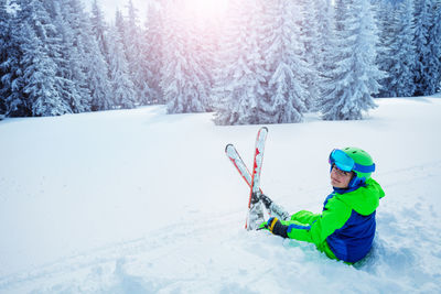 Portrait of boy skiing on snow covered field