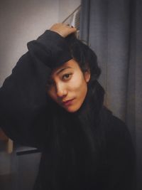 Portrait of young woman standing against wall