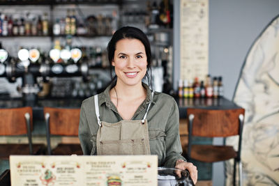 Portrait of smiling young owner standing at lectern in restaurant