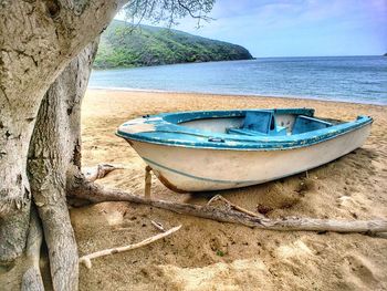 Boat moored on beach against sky