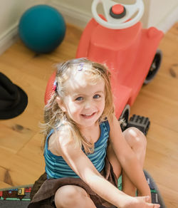 Portrait of smiling girl sitting on wooden floor