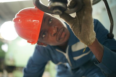 Close-up of man holding hardhat while standing outdoors