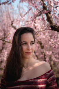 Portrait of beautiful woman against pink blossom trees