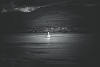 Sailboat in sea against mountains