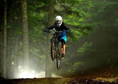 Man performing stunt with bicycle against trees