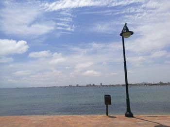 Street light by sea against sky