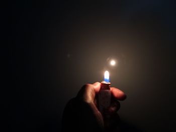 Close-up of hand holding lit candle