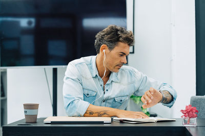 Portrait of a smiling man sitting at desktop in modern office