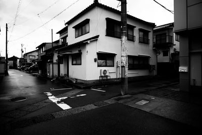 Empty road by buildings in city against sky