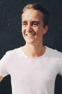 Portrait of young man standing against white wall