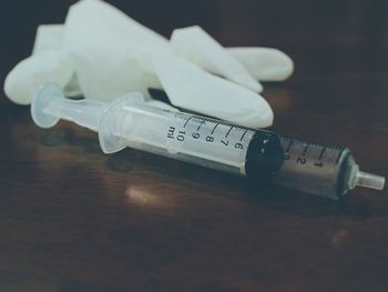 Close-up of gloves and syringe on table