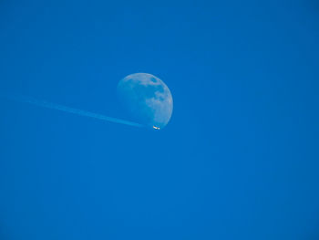 Low angle view of moon against clear blue sky