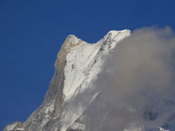 Low angle view of snowcapped mountain against blue sky