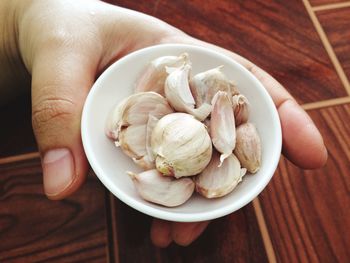 Close-up of hand holding garlic cloves in plate