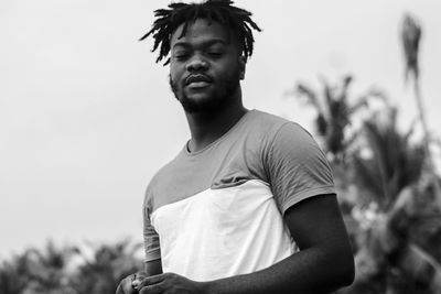 Portrait of young man standing against sky