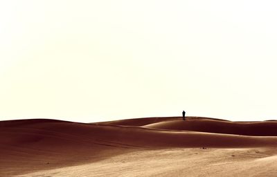 Mid distance of person standing on desert against clear sky