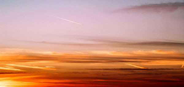 Aerial view of vapor trails in sky during sunset
