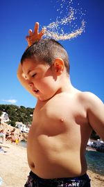 Close-up of shirtless boy against blue sky