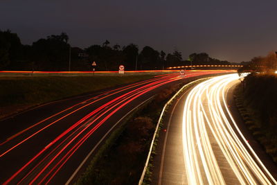 Light trails on road against sky at night