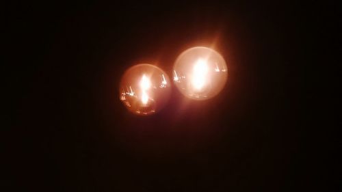 Close-up of illuminated light bulb against black background