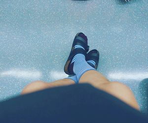 Low section of woman wearing socks and sandals resting on blue floor