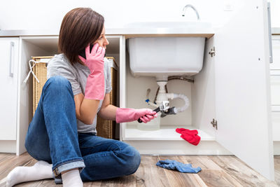 Side view of young woman using mobile phone while sitting at home