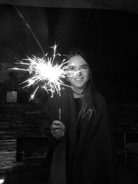 Portrait of woman holding sparkler at night