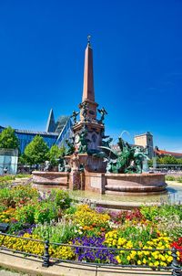 View of flowering plants by building against blue sky